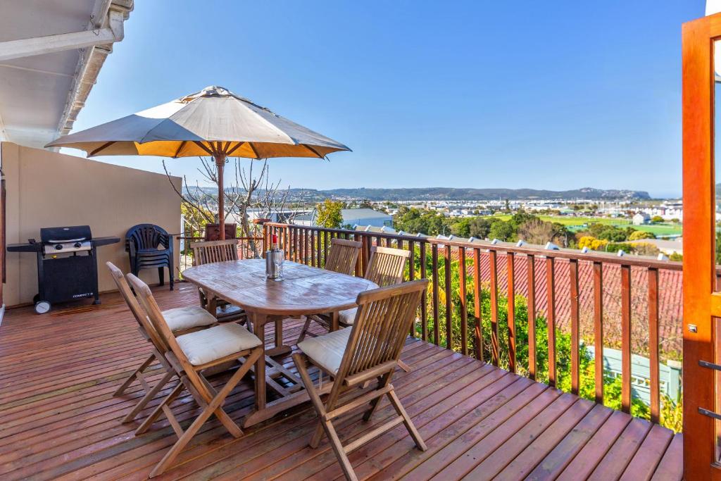 a wooden deck with a table and chairs and an umbrella at Prospect Cottage in Knysna