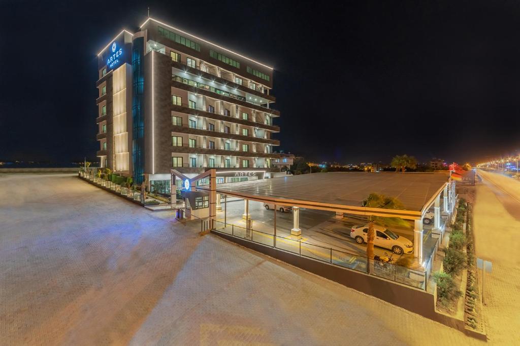 a hotel building with a parking lot at night at ARTES HOTEL in Hatay