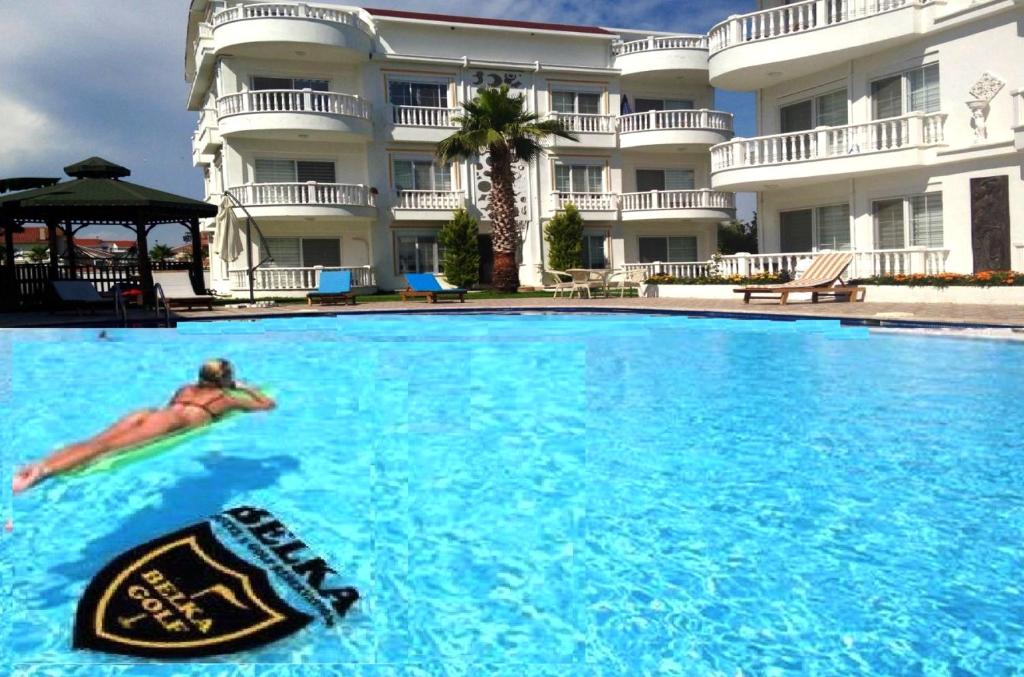 a person swimming in a pool in front of a hotel at BELKA GOLF RESİDENCE Dublex BELEK in Belek