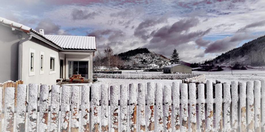 Biały dom za płotem ze śniegiem w obiekcie Bel Canto - Chambres d'hôtes Plateau de sault w mieście Roquefeuil