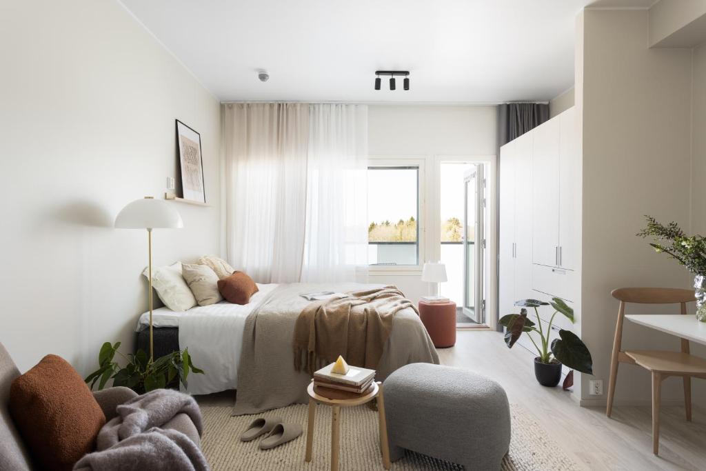 a white bedroom with a bed and a chair at Noli Myyrm&auml;ki in Vantaa