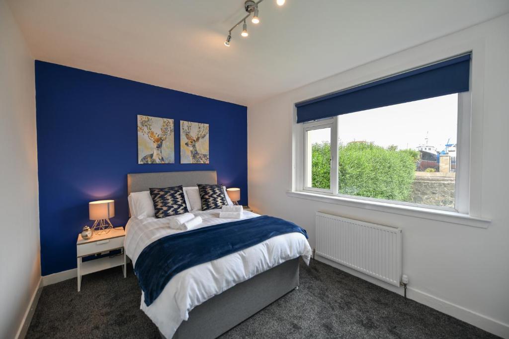 a blue bedroom with a bed and a window at Greensleeves Place in Troon