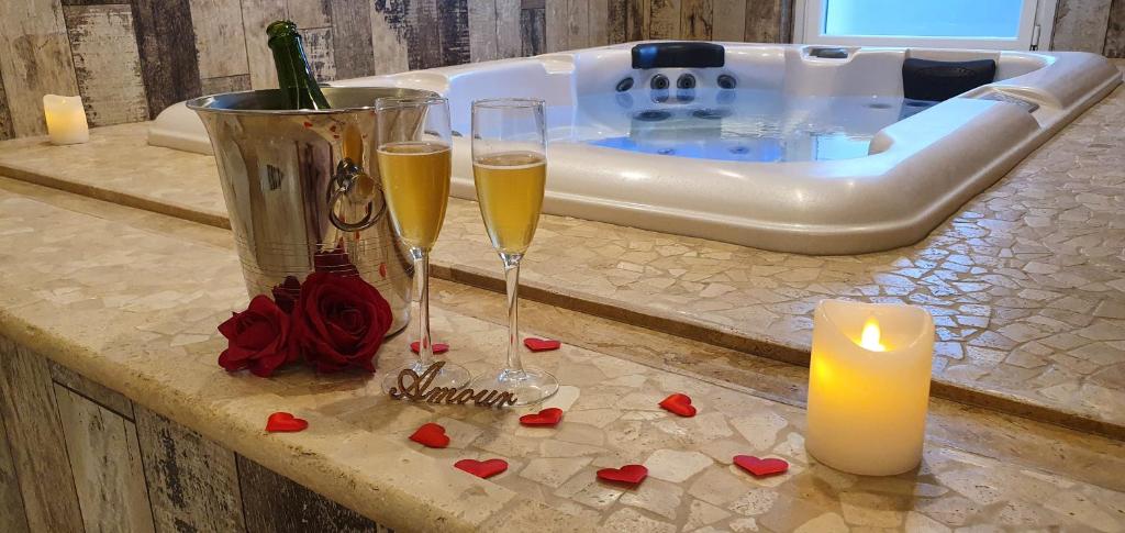 two glasses of champagne and a candle in front of a tub at Loveroom La Garçonn'Hyeres in Hyères