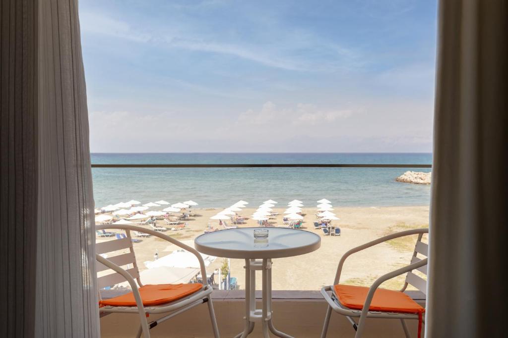 vista su una spiaggia con tavolo e sedie di Aqua Luxury Suites by Estia a Roda