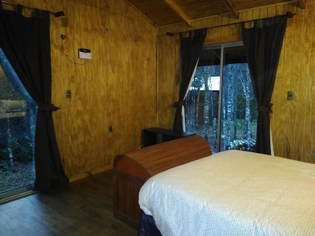 een slaapkamer met een bed en een raam bij Cabaña entre Arboles in Villarrica