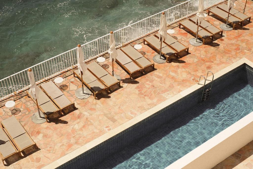 an overhead view of a pool with chairs and the water at Les Roches Rouges, a Beaumier hotel in Saint-Raphaël