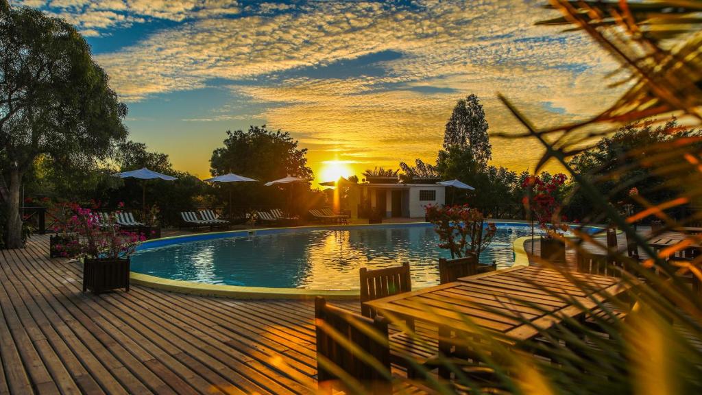 a swimming pool with a sunset in the background at KIMONY RESORT in Morondava