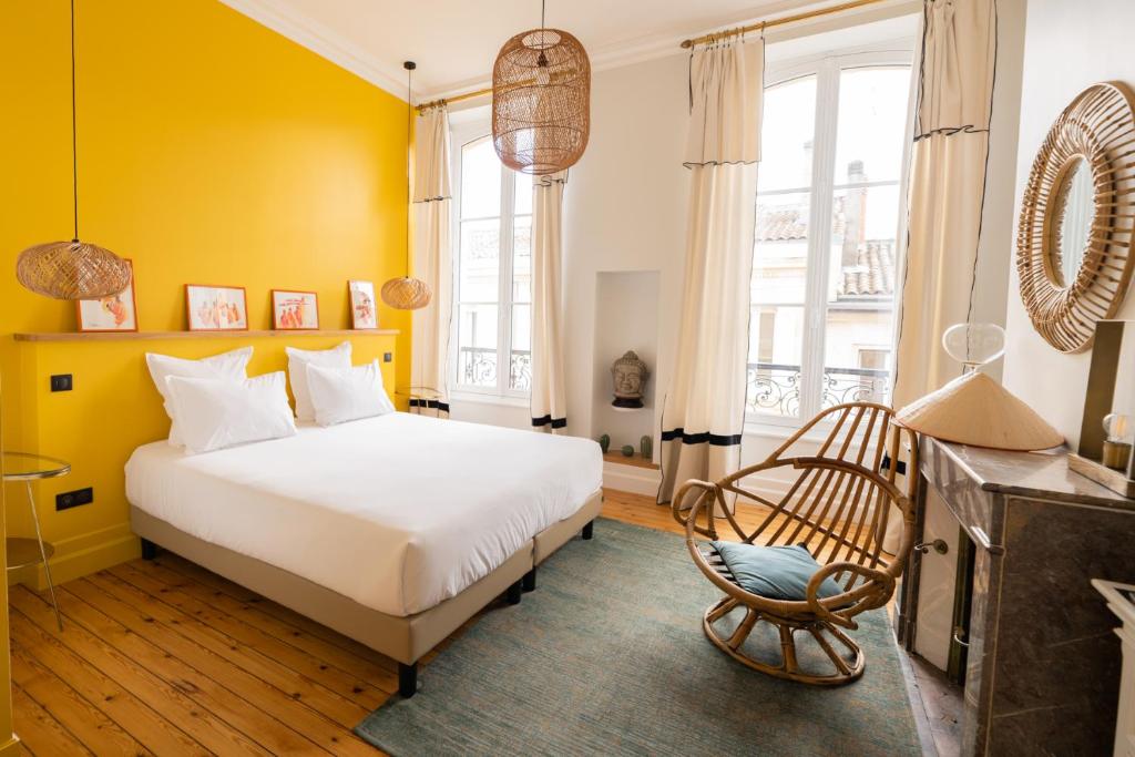 um quarto amarelo com uma cama e uma cadeira em Maison Manège Bordeaux Centre em Bordeaux