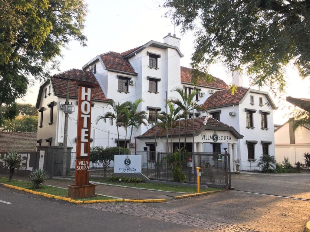 a white building with a hotel sign in front of it at Hotel Villa Souza Ltda in Santa Cruz do Sul
