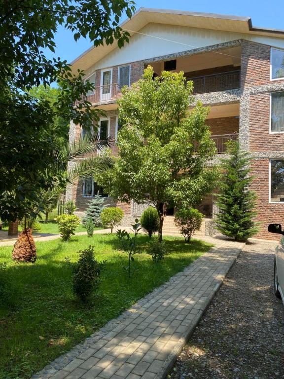 a brick building with a tree and a sidewalk at Guest house Shekvetili in Shekhvetili