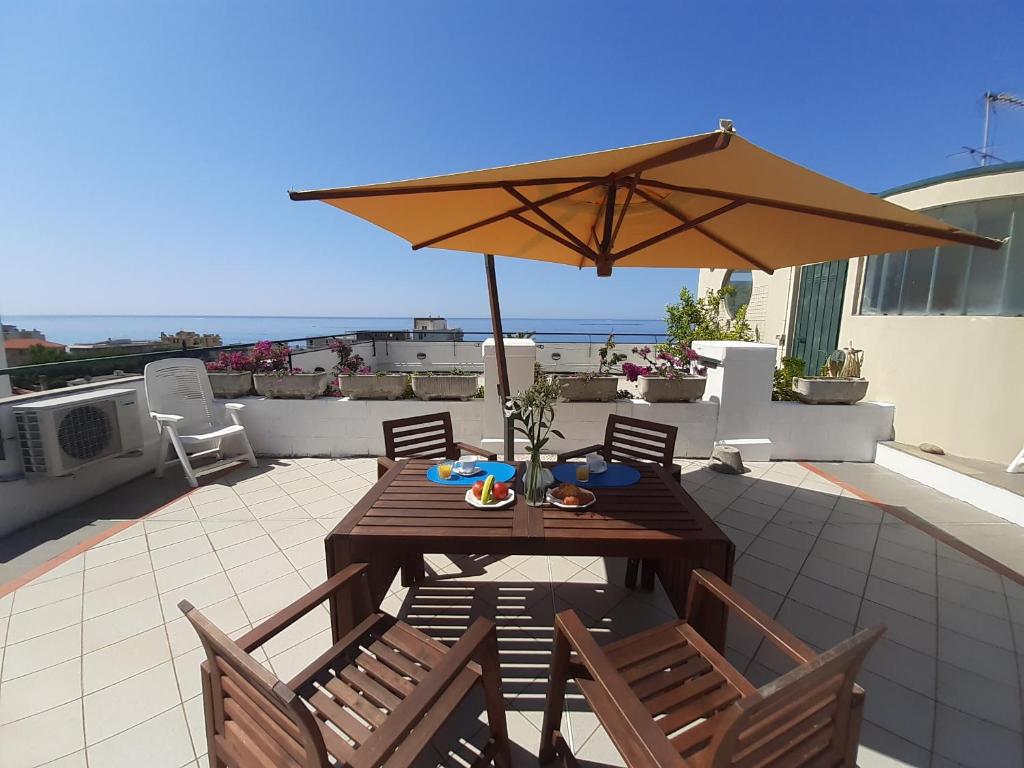 uma mesa de madeira com cadeiras e um guarda-sol num pátio em La terrazza tra il Mare e gli Ulivi by Holiday World em Lavagna