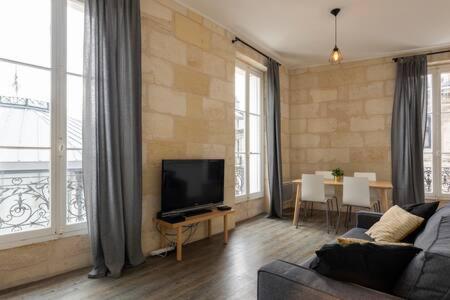 a living room with a couch and a flat screen tv at Appartement De Lerme in Bordeaux