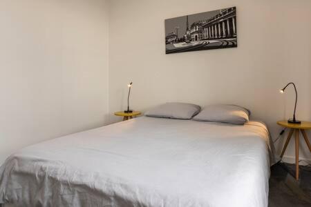 a white bed in a room with two tables at Appartement De Lerme in Bordeaux