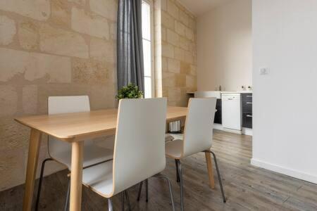 a dining room with a wooden table and white chairs at Appartement De Lerme in Bordeaux