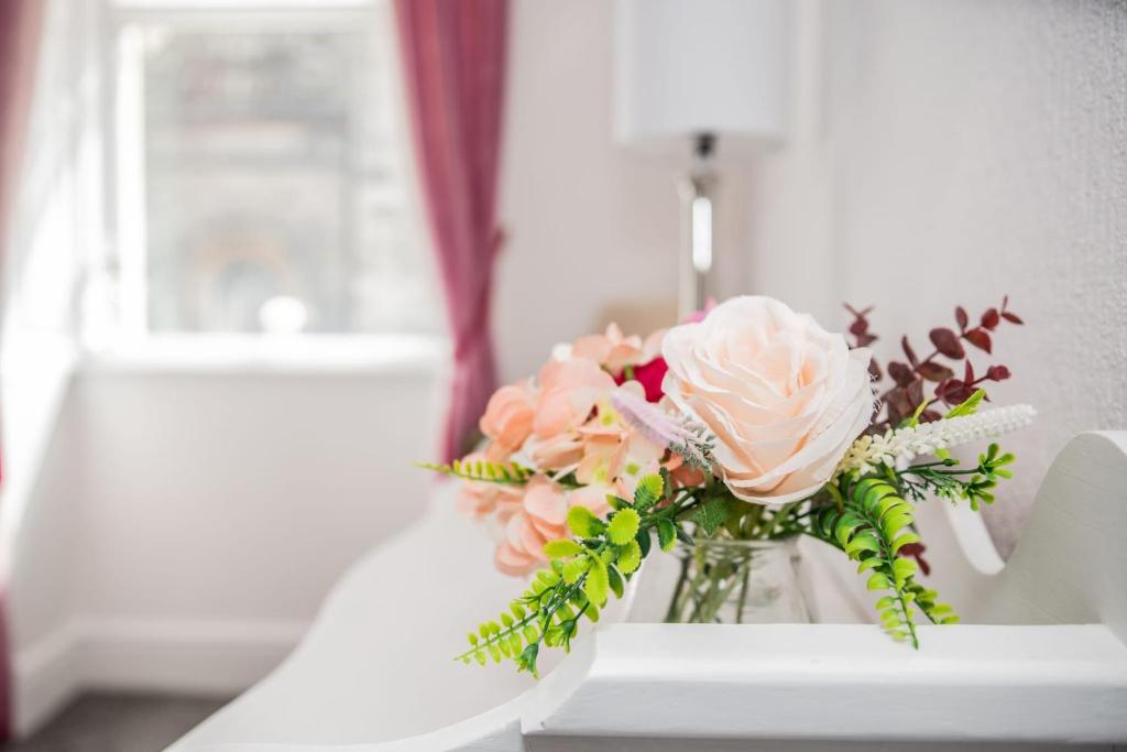 a vase of flowers sitting on a table at Rose Apartment 2-Bed Town Centre Apartment in Ayr in Ayr