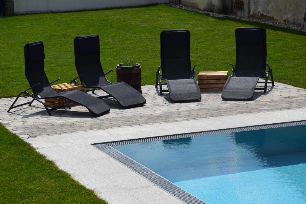 four chairs and a swimming pool in a yard at Rebenhof Schwalm in Herrnbaumgarten