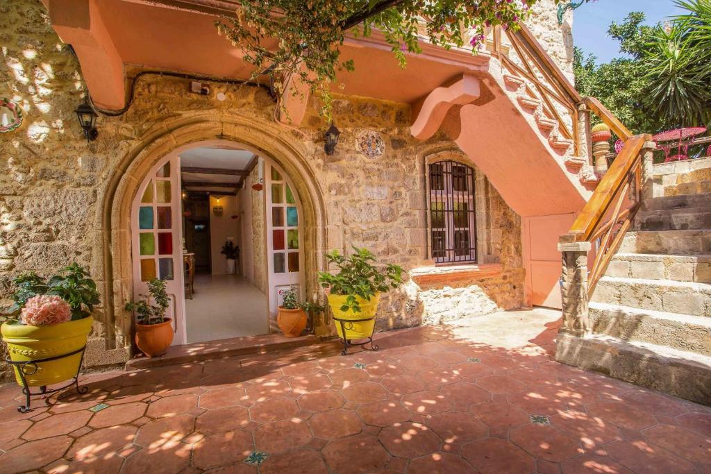 uma entrada para uma casa com vasos de plantas e escadas em Attiki Hotel in Ilha de Rhodes