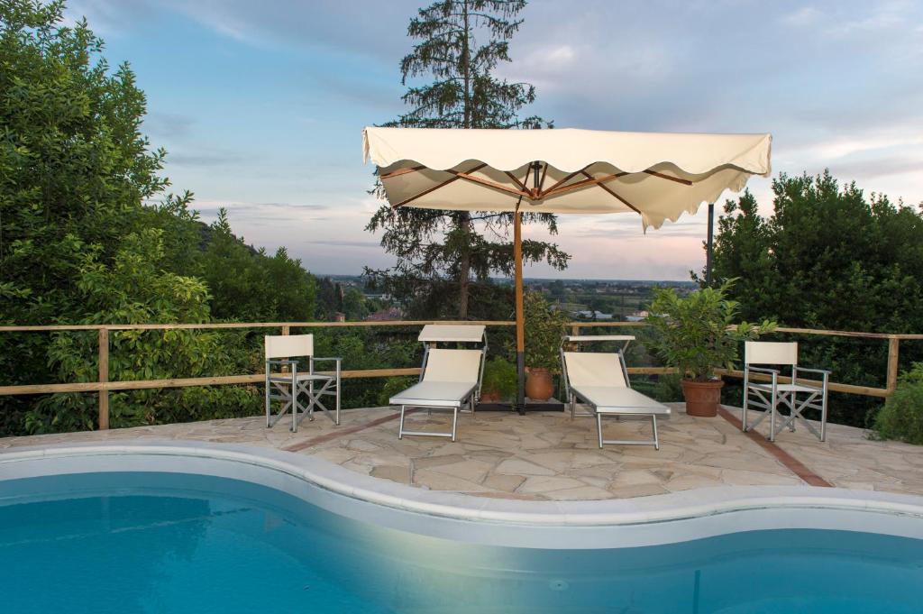 a patio area with a pool, chairs, and umbrellas at Villa Alta - Residenza d'epoca con piscina in San Giuliano Terme