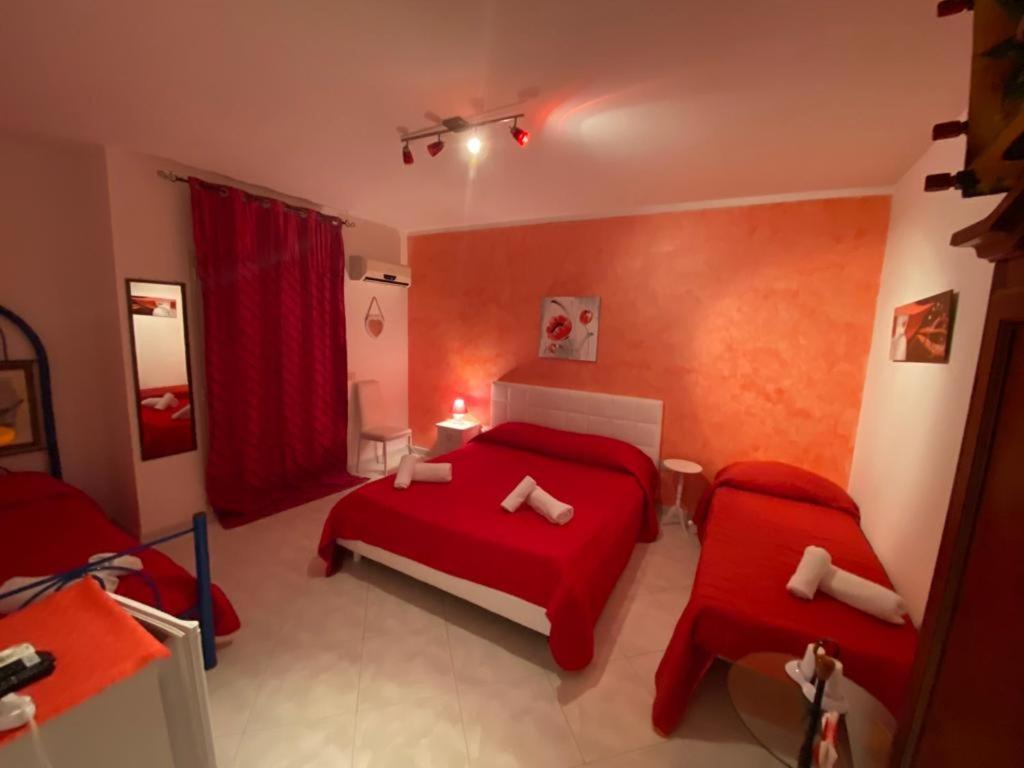 a red bedroom with two beds and red curtains at Colomba Bianca in Marsala