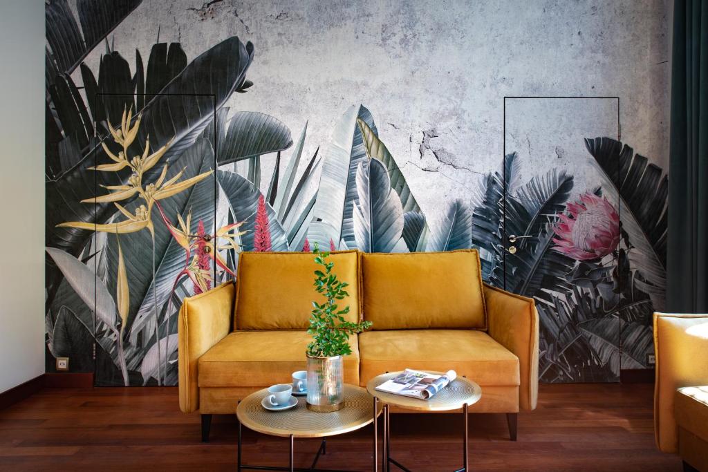 a living room with a yellow couch and a tropical mural at Krakowhomes in Kraków