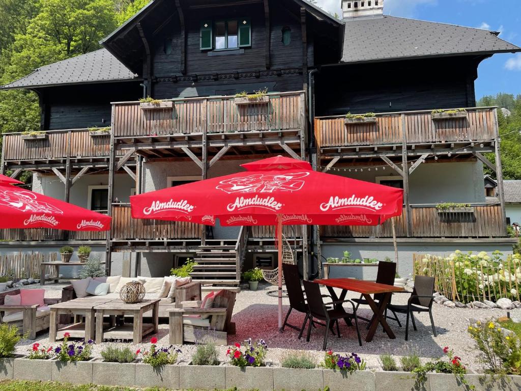 two red umbrellas and tables and chairs in front of a building at Gesäuse-Lodge in Gstatterboden