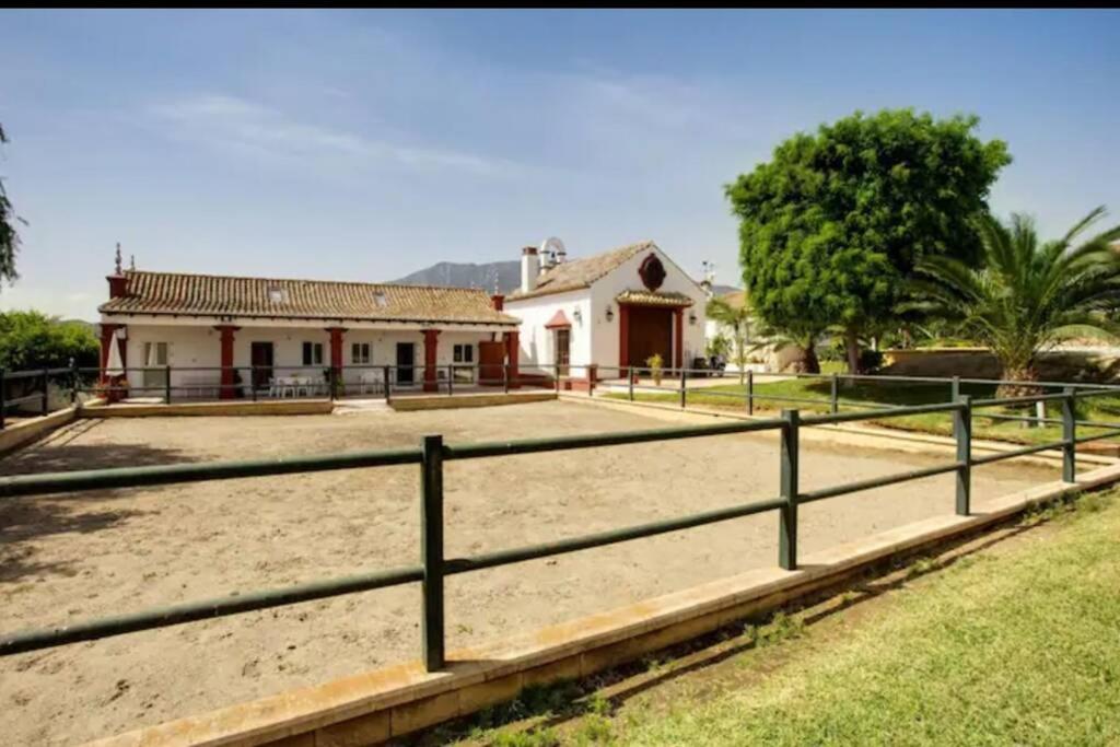 une maison avec une clôture devant un champ dans l'établissement Finca El Altabacar - Casa Rural - Playa, à Mijas