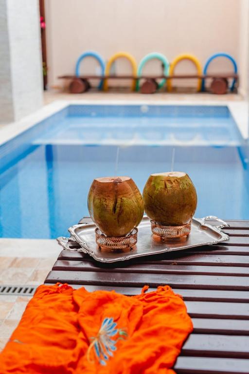 two bowls on a tray next to a swimming pool at Pousada Oásis in Peruíbe