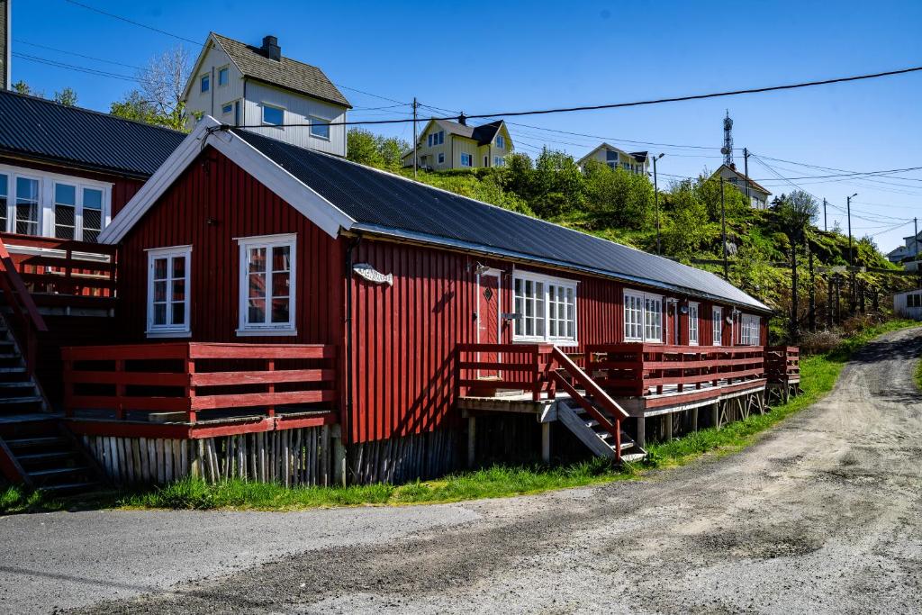 a red building with white windows on a street at Klingenberg Rorbuer in Sørvågen