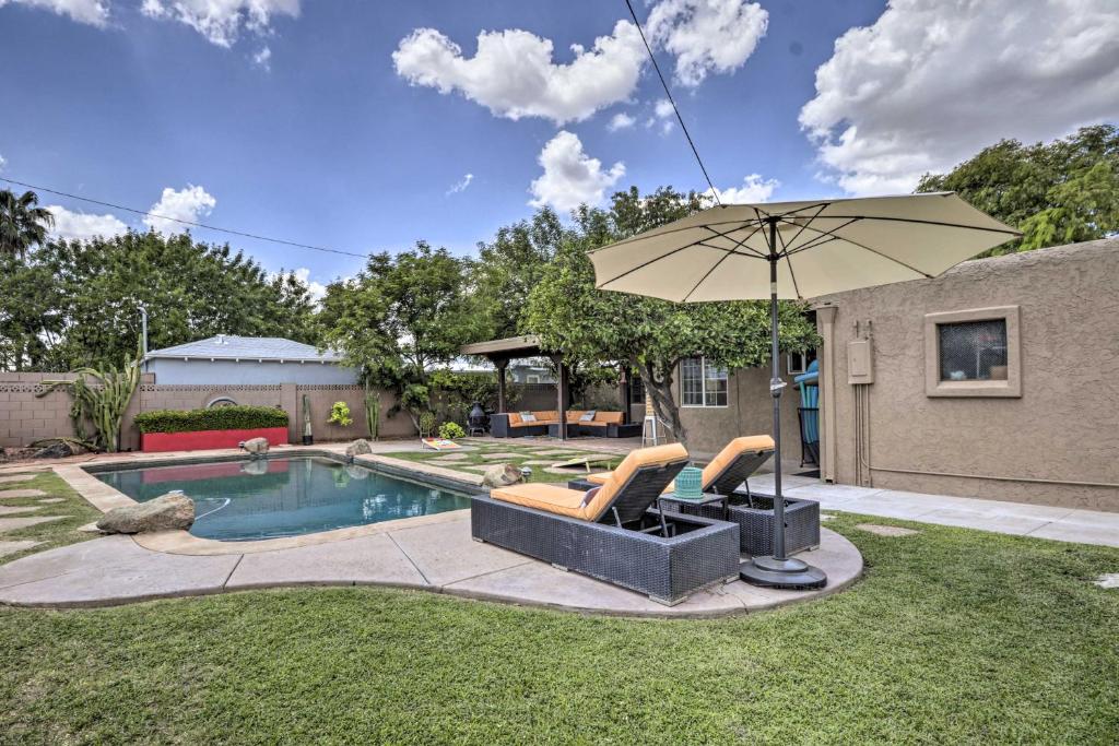 a pool with two chairs and an umbrella at Phoenix Getaway with Private Pool and Grass Yard! in Phoenix