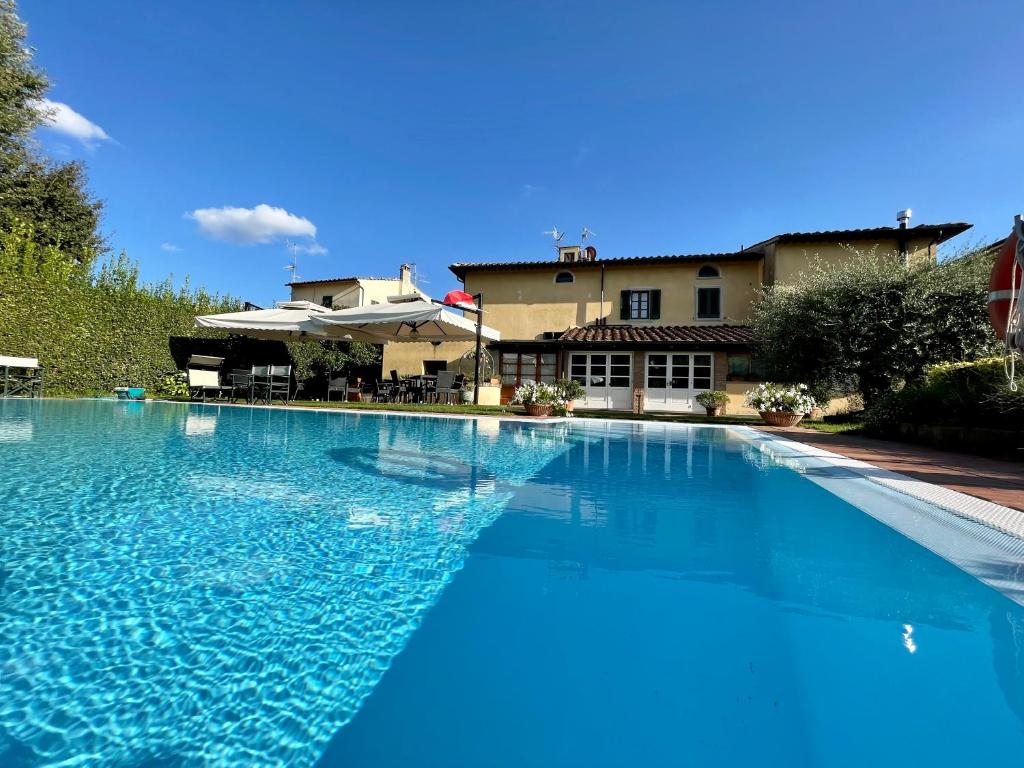 a large blue swimming pool in front of a house at Villa Maria - b&b di Charme in Vicopisano