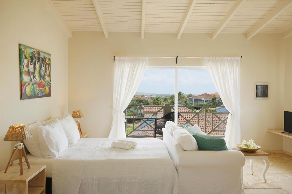 een slaapkamer met een wit bed en een balkon bij Ocean Breeze Boutique Hotel & Marina in Kralendijk