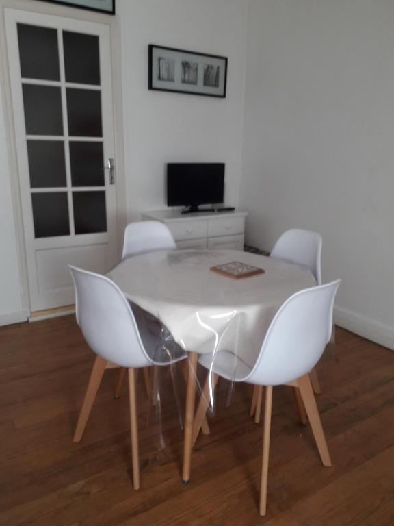 une table à manger blanche avec des chaises blanches et une télévision dans l'établissement Appartement Fort-Mahon Plage, à Fort-Mahon-Plage