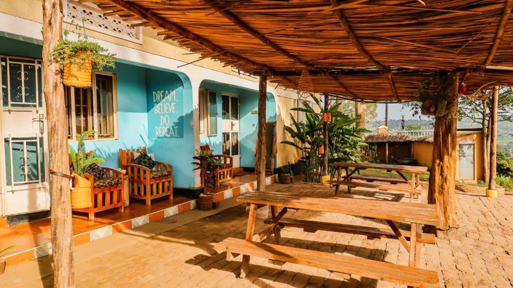a patio with wooden benches and a blue building at Villa Katwe in Masaka