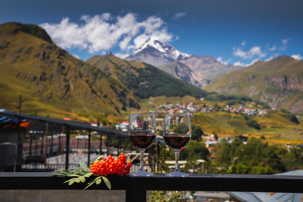 two glasses of wine on a table with a view of a mountain at Hotel INSIDE Kazbegi in Stepantsminda
