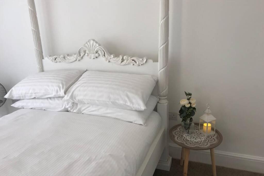 Una cama con sábanas blancas y una mesa con una vela. en Beautiful 2 bed flat in the heart of Lynton Devon, en Lynton