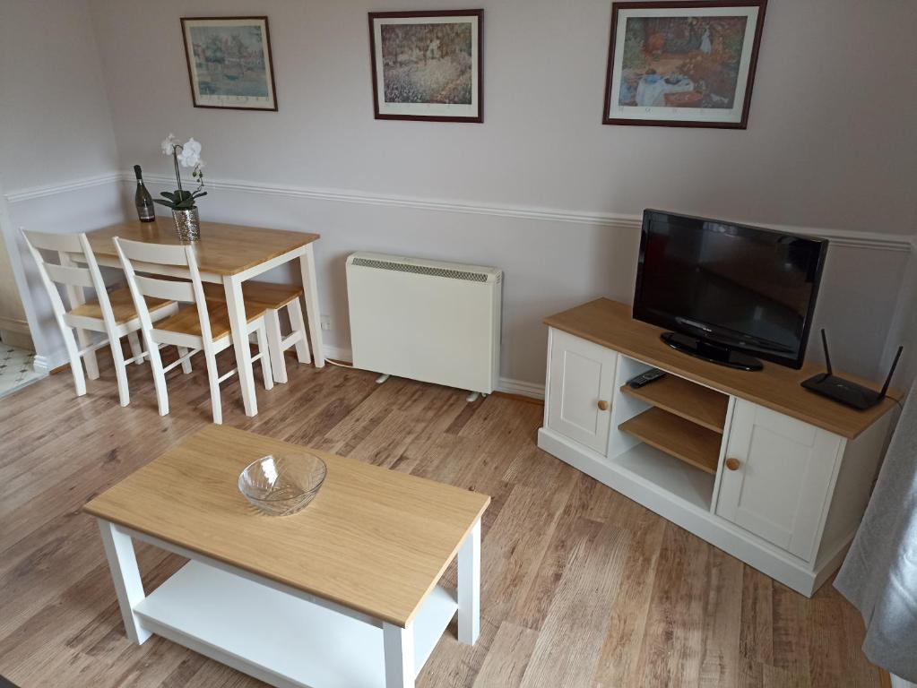 a living room with a television and a table with chairs at Grant Close in Wickford