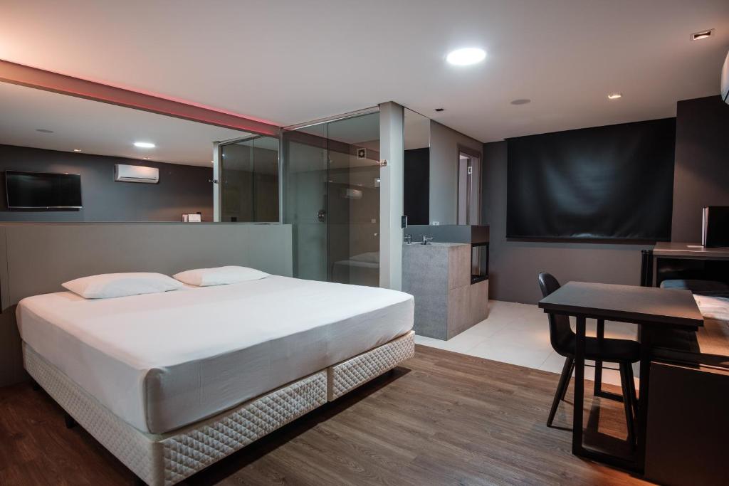 1 Schlafzimmer mit einem großen Bett und einem Badezimmer in der Unterkunft Motel Della Montagna (Adult Only) in Bento Gonçalves
