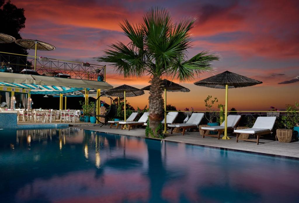 a pool with a palm tree and chairs and umbrellas at Kastro Maistro in Lefkada Town