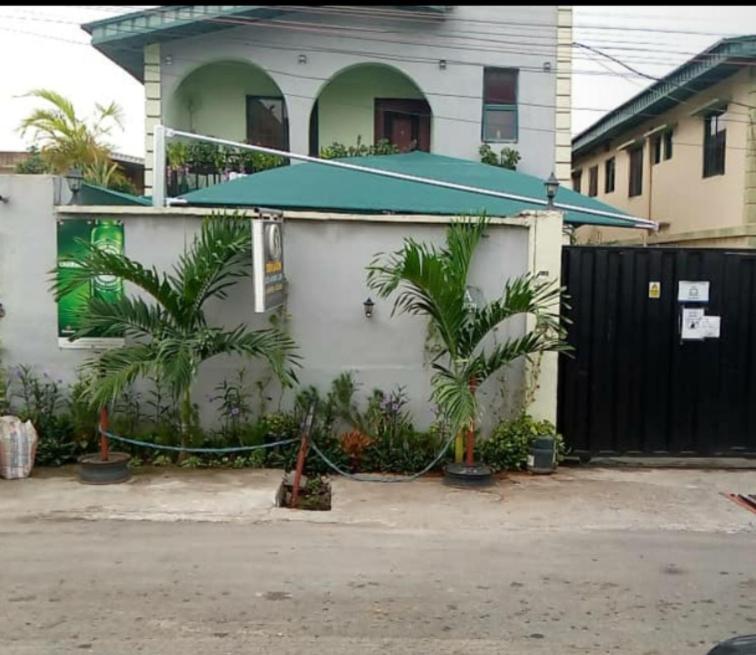 a house with a fence and palm trees in front of it at StayCation Suites And Apartment in Lagos