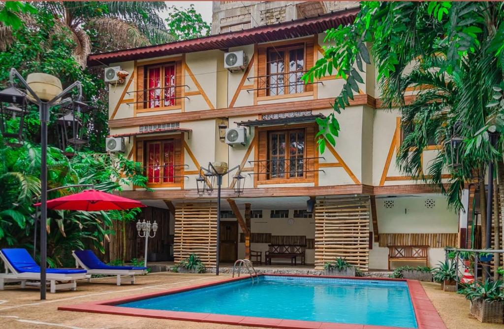 a house with a swimming pool in front of it at Boutique Hotel Pavillon in Abidjan
