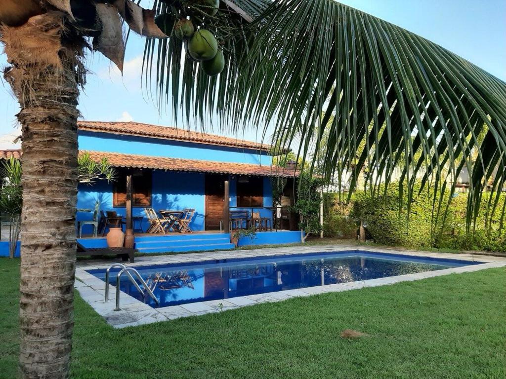 a house with a swimming pool next to a palm tree at Casa Azul Praia da Pipa Condomínio Pipa Natureza in Pipa