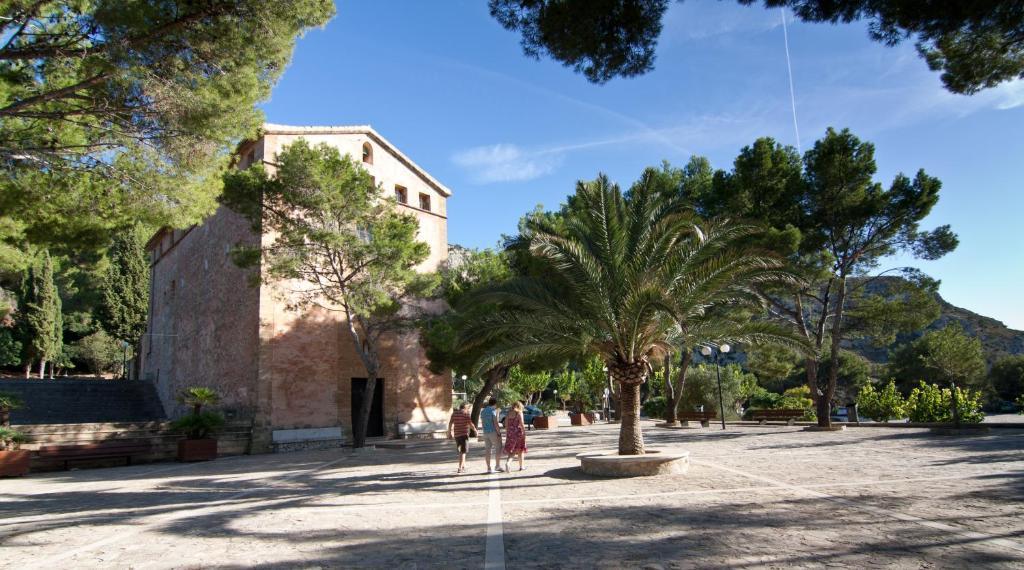 two people walking down a street with palm trees at Petit Hotel Hostatgeria La Victoria in Alcudia