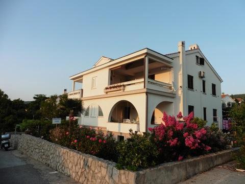 una grande casa bianca con dei fiori davanti di Apartments Biserka a Punat