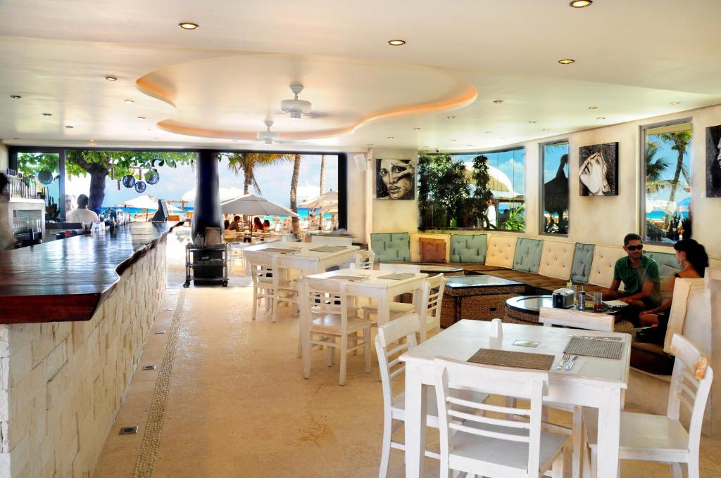 a restaurant with white tables and chairs and a bar at El Taj Oceanfront and Beachside Condo Hotel in Playa del Carmen