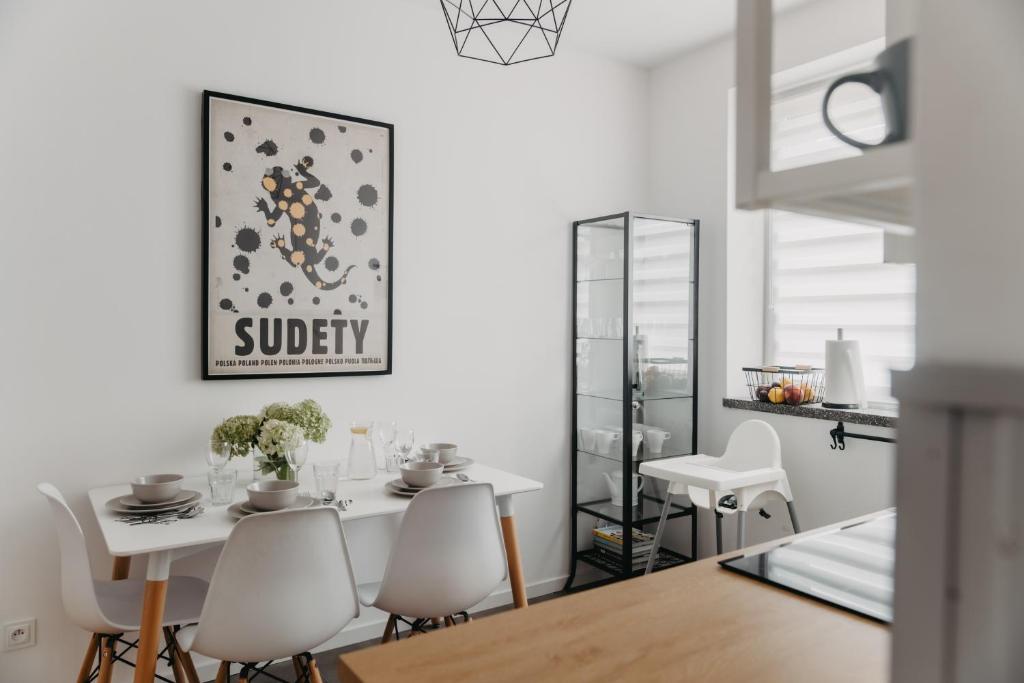 a dining room with a white table and chairs at Jeleni Zakątek - apartament w stolicy Karkonoszy in Jelenia Góra