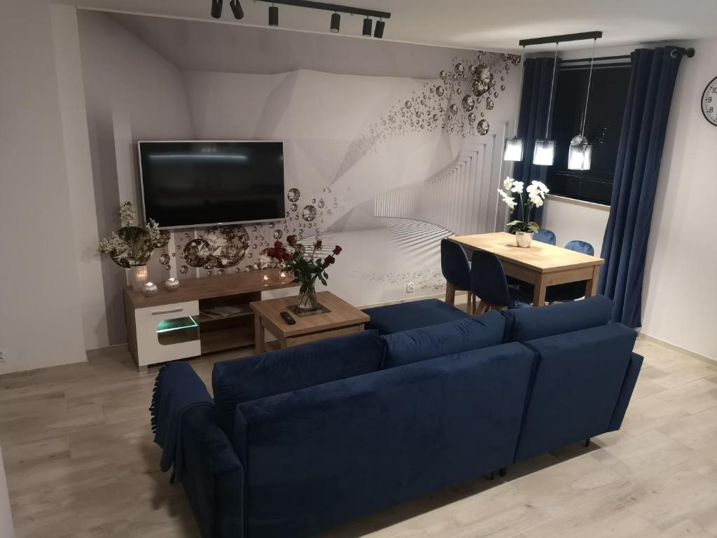 uma sala de estar com um sofá azul e uma mesa em Apertament KOSMOS em Zabrze