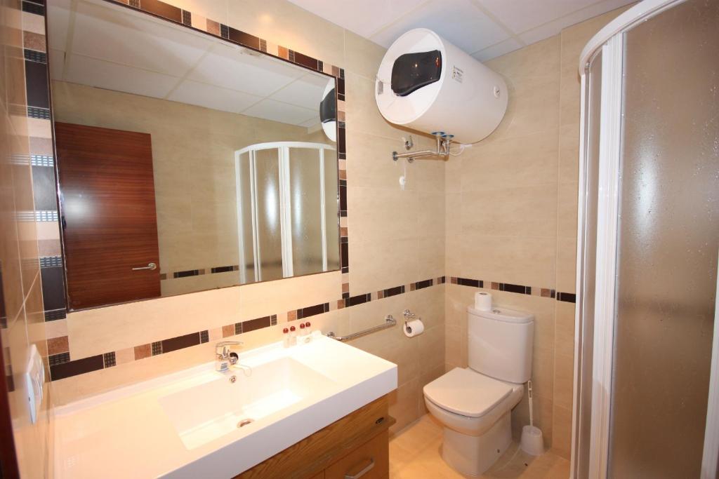 Un baño con lavabo, inodoro y espejo. en Apartamentos Rurales Campillo, en Arroyo Frío
