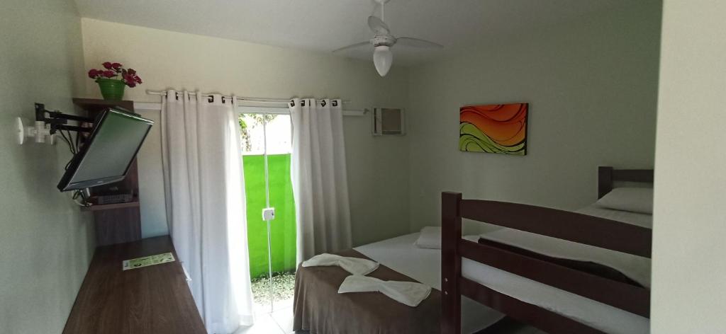 a bedroom with a bed and a window and a television at Sun Suítes in Ubatuba