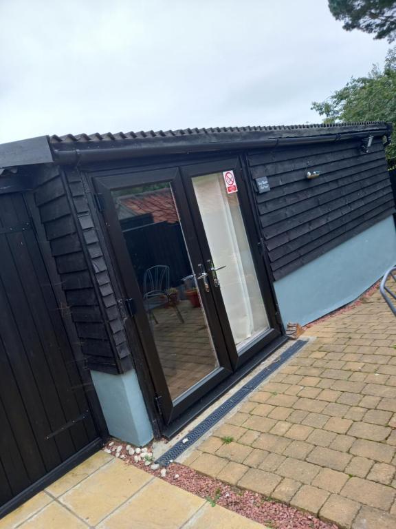 a black shed with sliding glass doors on a patio at 1 ivy cottages the street norton subcourse NR146RS in Norwich
