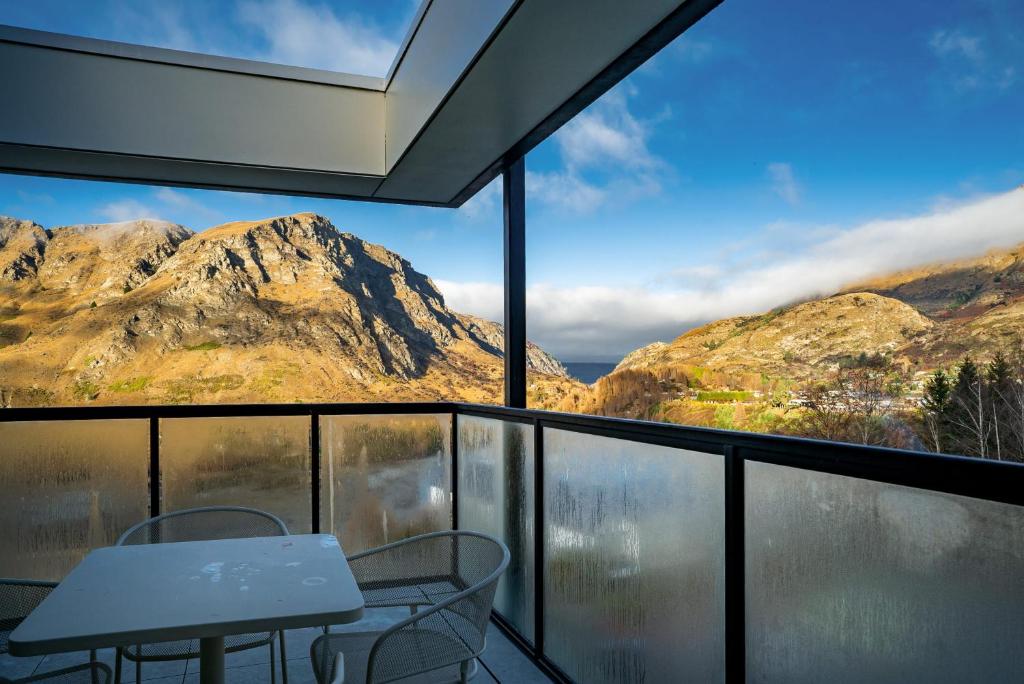 a room with a table and chairs and mountains at Riverview Penthouse - Apartment 19 in Queenstown